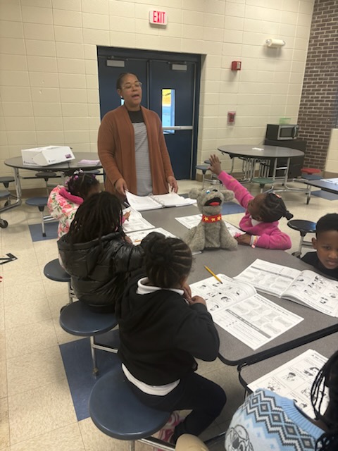 Above and Beyond Students staff member leads a small-group lesson during a free after-school program at Westerly Hills Academy in Charlotte, NC, as elementary students work on worksheets and participate in classroom enrichment.