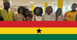 Above and Beyond Students campers and two staff members celebrate Ghana Day during the Around the World in 3 Days activity, posing together in the school cafeteria. The photo has a red, yellow, and green Ghana flag graphic at the bottom.