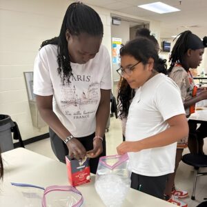 A camp counselor and student mix ice cream salt and ice to make homemade ice cream during Above and Beyond Students' free summer camp at Ranson Middle School in Charlotte, NC.