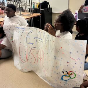 Students hold their hand-colored Team USA banner during the ABS Summer Olympics at Above and Beyond Students' free summer camp, Ranson Middle School, Charlotte, NC.