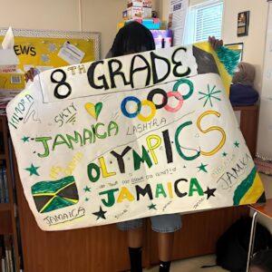 A student displays the 8th grade Jamaica team banner during Above and Beyond Students' free summer camp's Olympics Day at Ranson Middle School in Charlotte, NC.